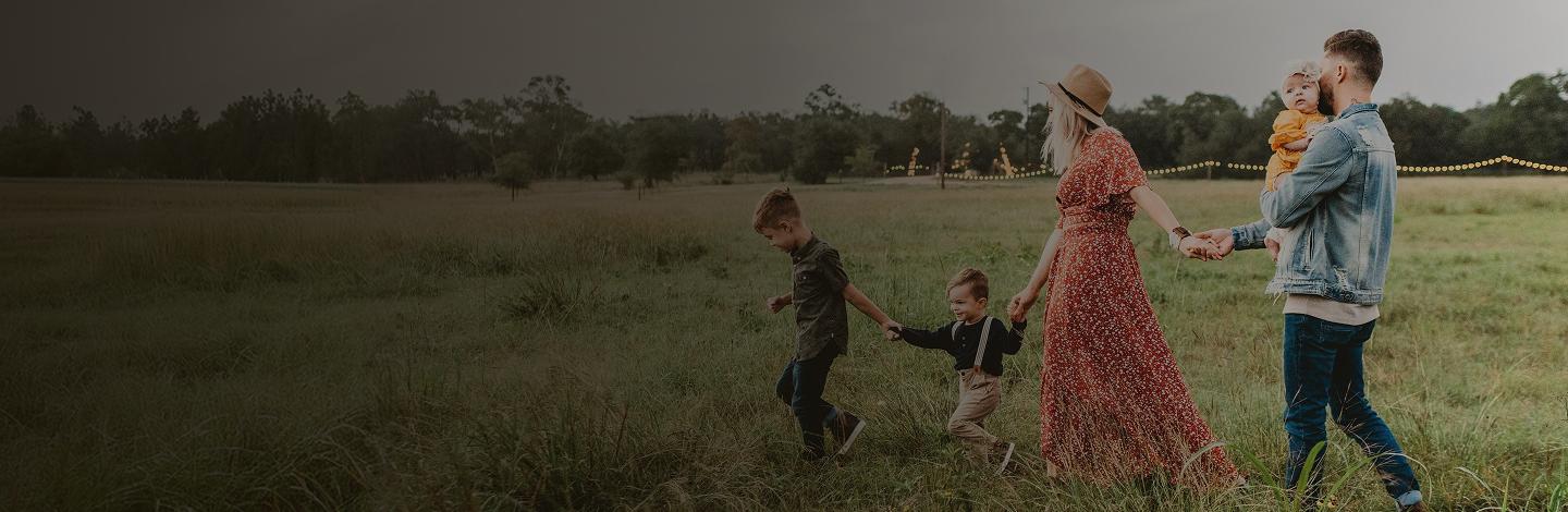A family walking together outdoors in a sunlit field